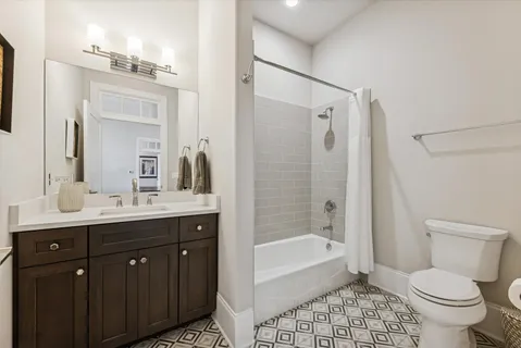 a bathroom with a bathtub shower sink vanity mirror and toilet