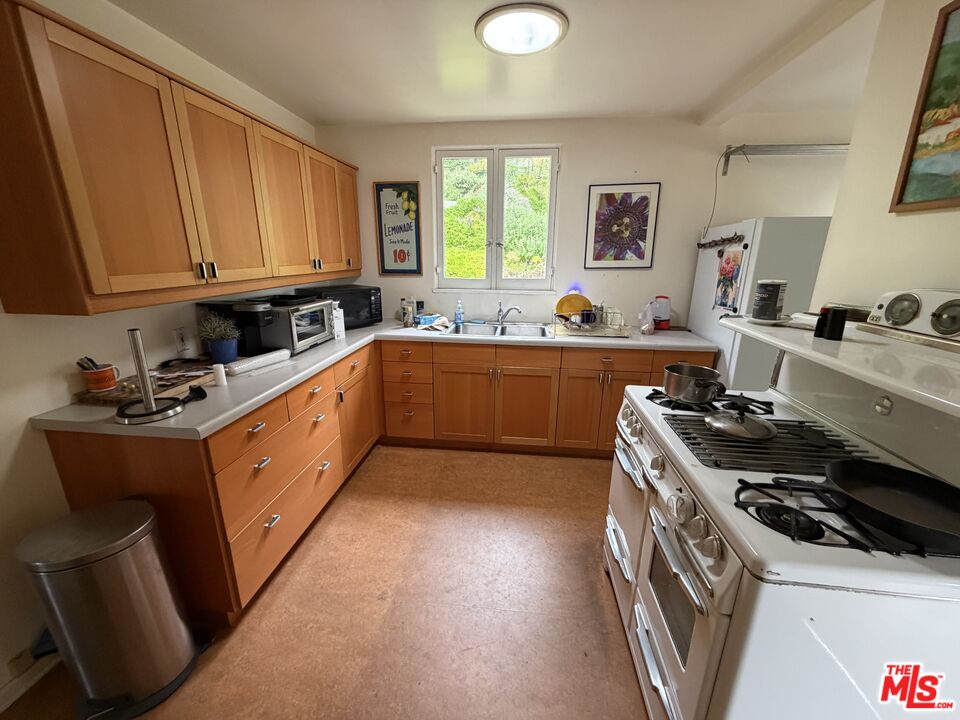 439 Mesa Road Santa Monica, CA 90402 - Photo 4 of 20 a kitchen with wooden cabinets and a stove top oven