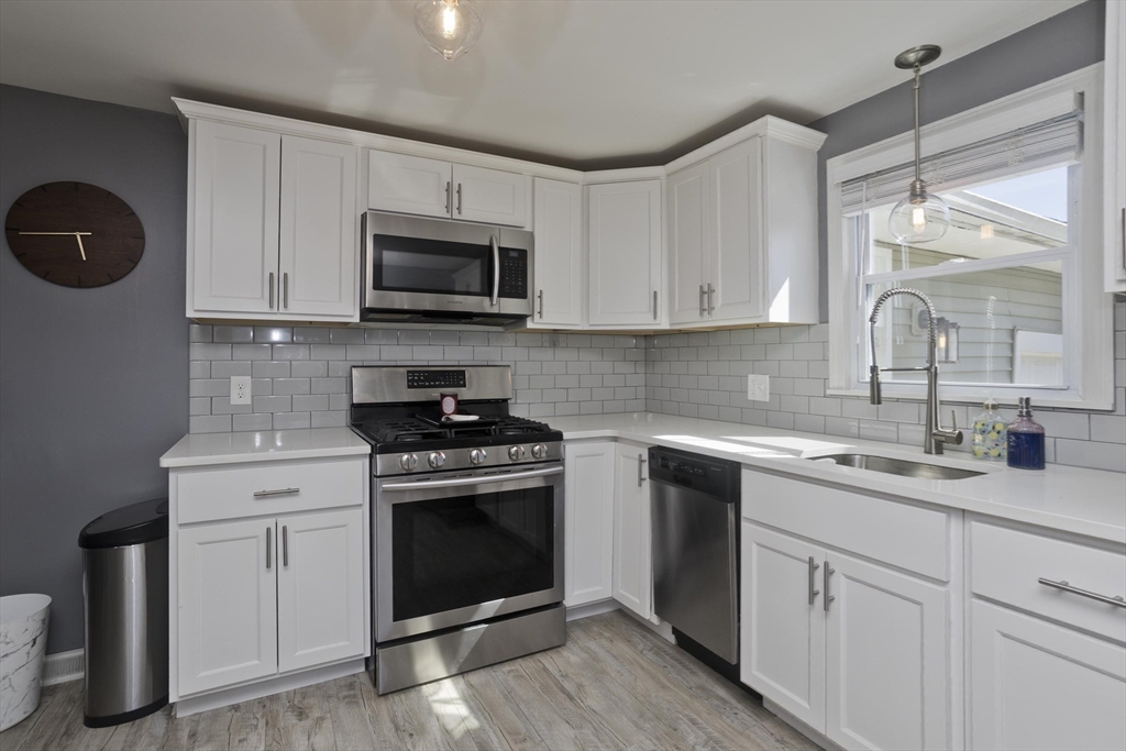 43 Rochester Street Chicopee, MA 01020 - Photo 8 of 38 a kitchen with stainless steel appliances granite countertop a sink a stove and microwave with wooden floor