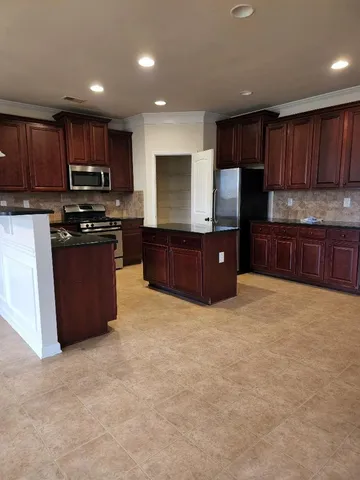 a kitchen with stainless steel appliances granite countertop a refrigerator and a stove top oven