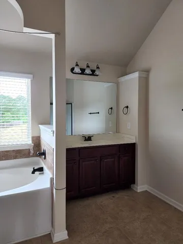 a spacious bathroom with a tub sink and mirror