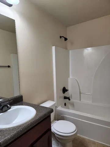 a bathroom with a granite countertop sink toilet a mirror and shower