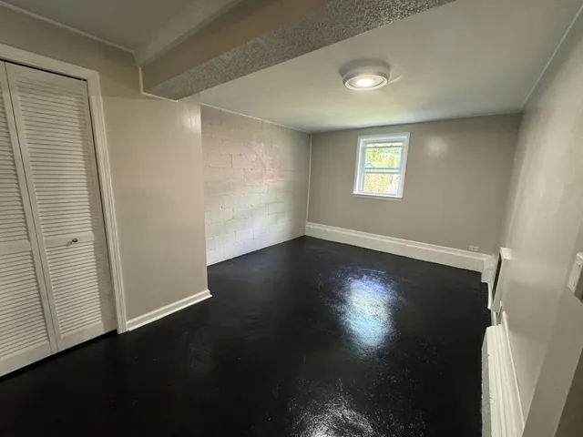 an empty room with wooden floor and windows with curtains