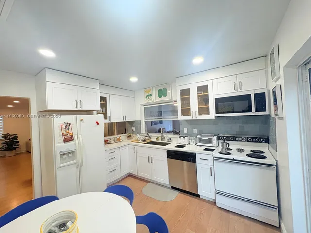 a kitchen with a sink a stove a refrigerator cabinets and a dining table