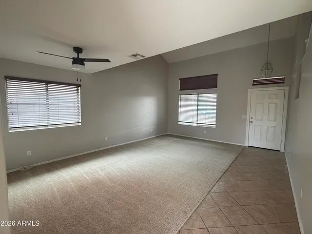 an empty room with windows and ceiling fan