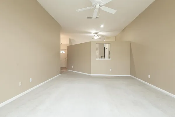 an empty room with chandelier fan and windows
