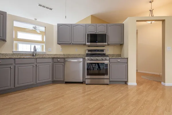 a kitchen with stainless steel appliances granite countertop a stove a sink and a microwave
