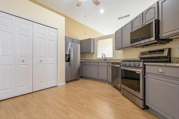 a kitchen with stainless steel appliances granite countertop a stove a sink and a microwave