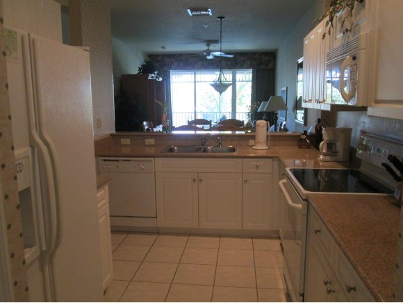 7920 Mahogany Run Lane, Unit 1024 Naples, FL 34113 - Photo 6 of 18 a kitchen with a sink a stove a refrigerator and cabinets