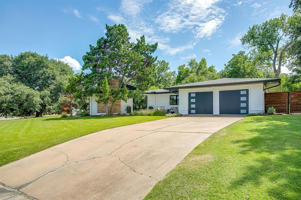 6700 Fortune Road Fort Worth, TX 76116 - Photo 3 of 40 Contemporary white exterior with a flat roofline, featuring two dark grey garage doors with rectangular window inserts