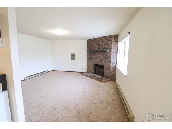 a view of an empty room with a fireplace and a window