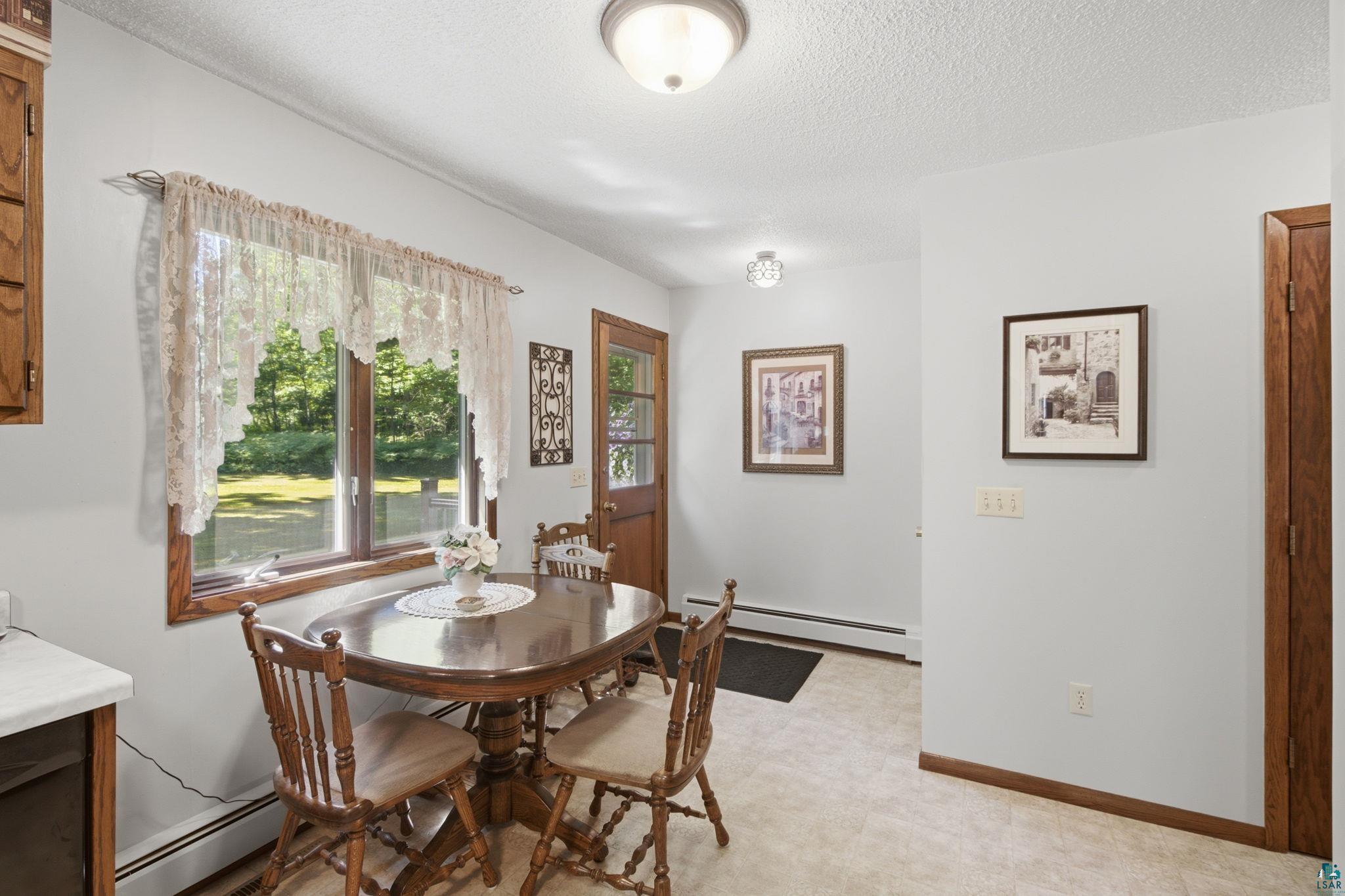 27485 South Kane Road Ashland, WI 54806 - Photo 11 of 35 Dining area featuring a wood-framed window, light-toned flooring, and a wood-paneled door