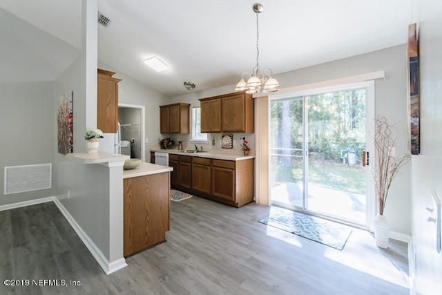 144 Brickyard Road Middleburg, FL 32068 - Photo 4 of 17 a kitchen with stainless steel appliances granite countertop a stove top oven a refrigerator a sink and a dining table with wooden floor