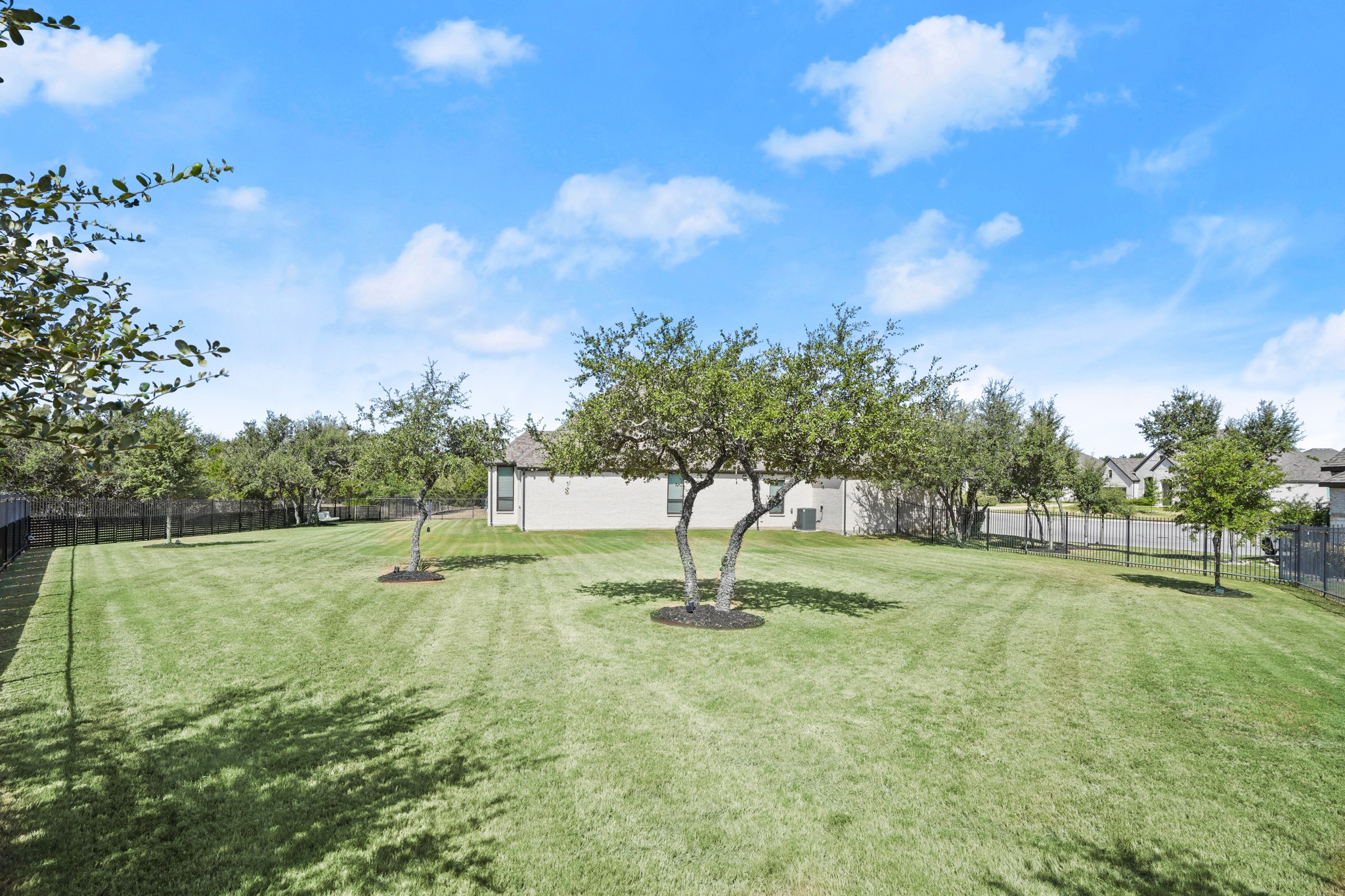 154 LITTLE Strm Cove Austin, TX 78737 - Photo 34 of 37 Mature trees shade a massive manicured lawn enclosed by security fencing.