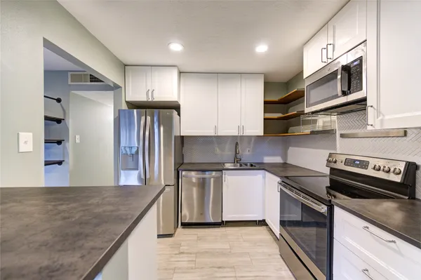 a kitchen with stainless steel appliances granite countertop a refrigerator a stove and a sink