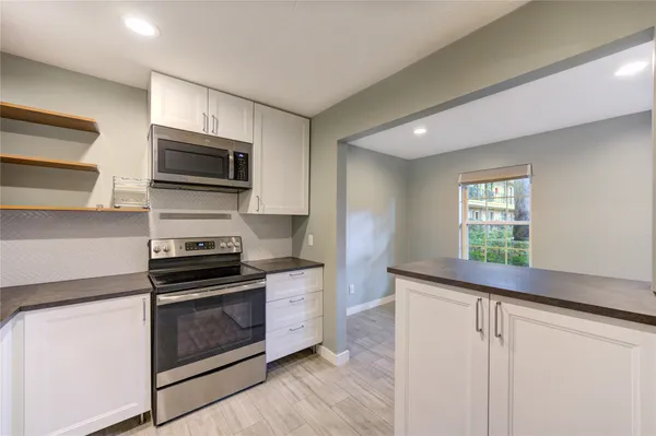 a kitchen with kitchen island white cabinets appliances and a window