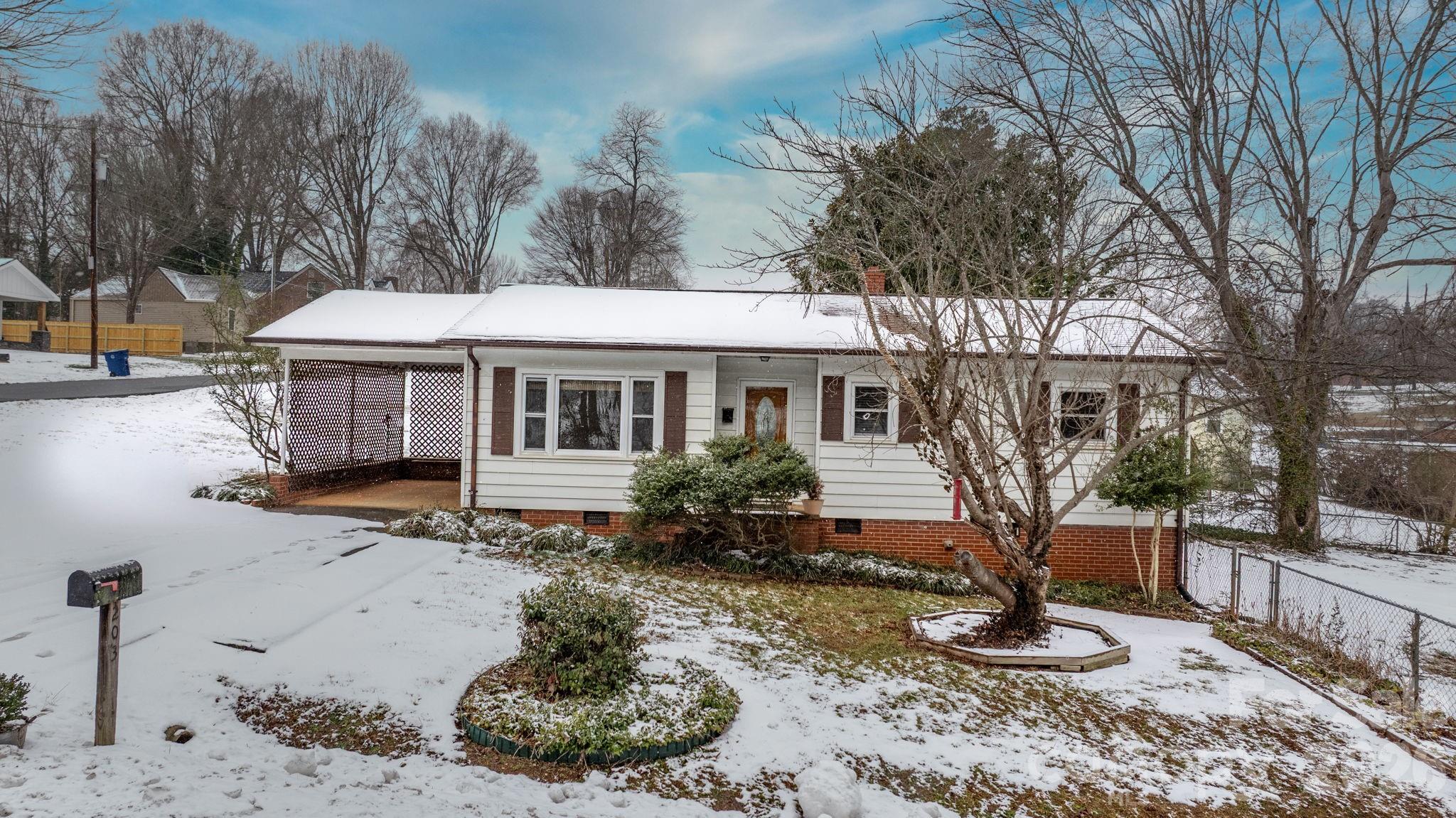 a front view of a house with a yard covered in snow