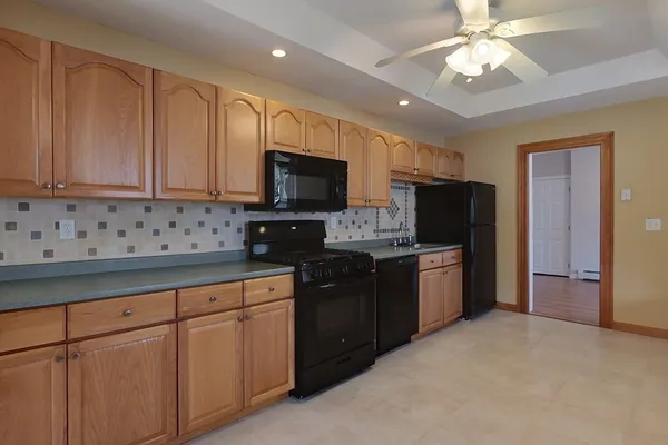 a kitchen with stainless steel appliances granite countertop a refrigerator a sink dishwasher a stove and white cabinets with wooden floor