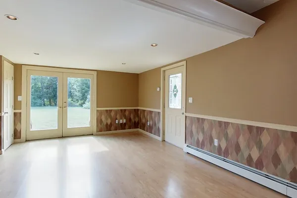 a view of an empty room with wooden floor and a window
