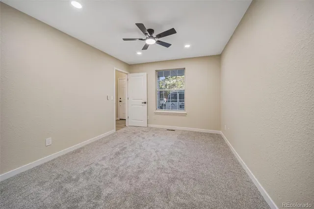 an empty room with windows and fan