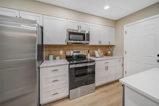 a kitchen with white cabinets and stainless steel appliances