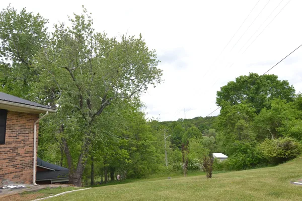 a view of a big house with a big yard and large trees