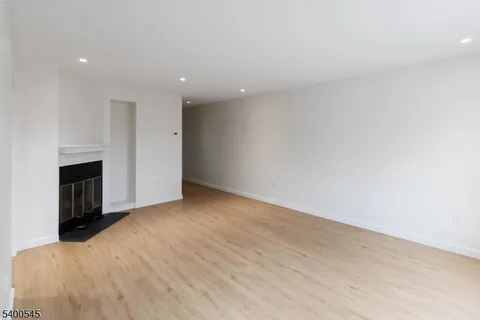 a view of empty room with wooden floor and fireplace