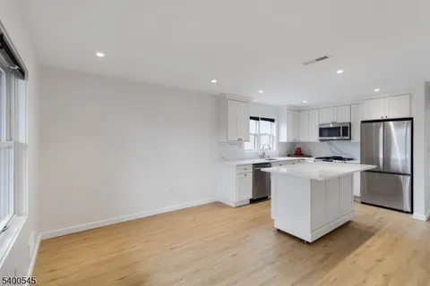 a kitchen with stainless steel appliances a refrigerator sink and white cabinets