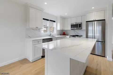 a kitchen with kitchen island a white cabinets and refrigerator