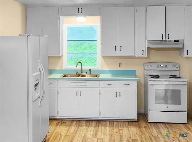 a kitchen with granite countertop white cabinets and white appliances