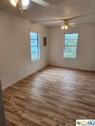 a view of an empty room with wooden floor and a window