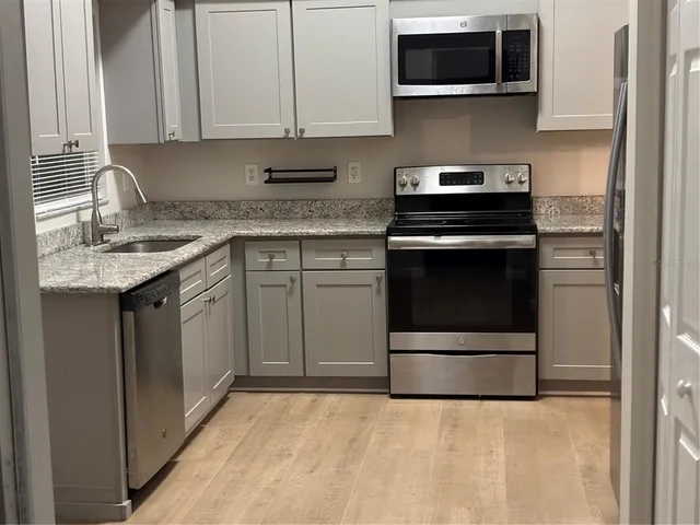 a kitchen with stainless steel appliances granite countertop a sink and a microwave