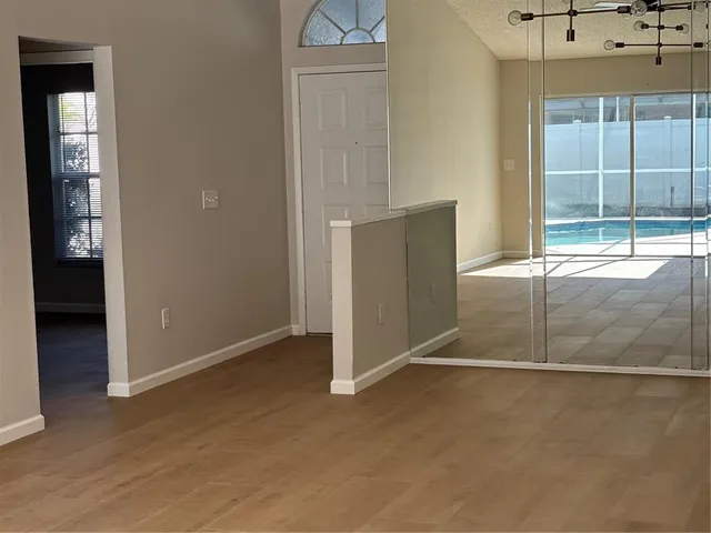a view of empty room with wooden floor and fan