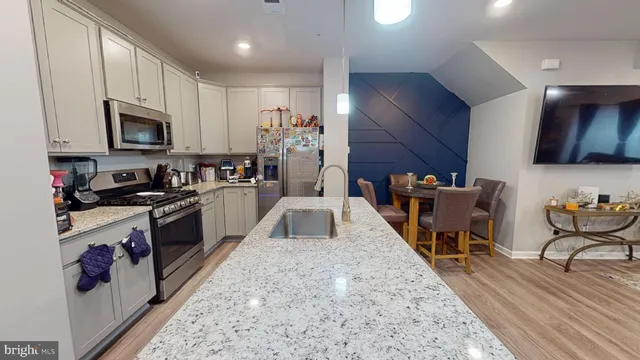 a large kitchen with stainless steel appliances granite countertop a stove a sink dishwasher a microwave oven with cabinets and wooden floor