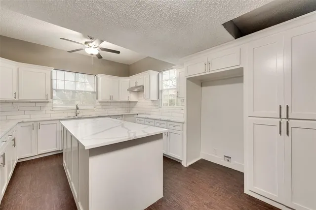 a kitchen with a sink dishwasher a refrigerator and white cabinets