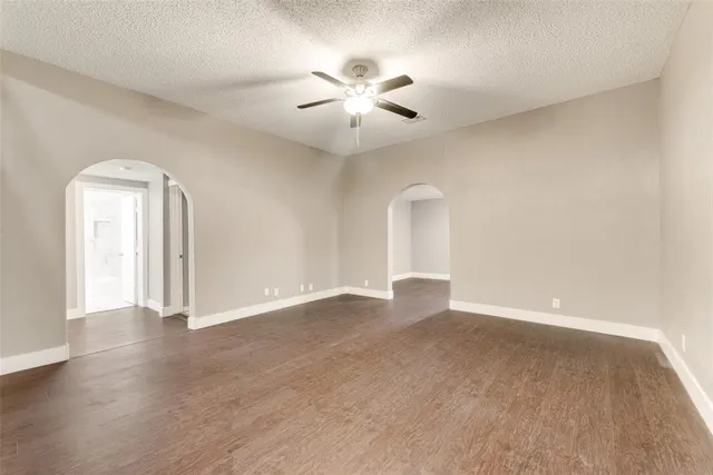 an empty room with wooden floor chandelier fan and windows