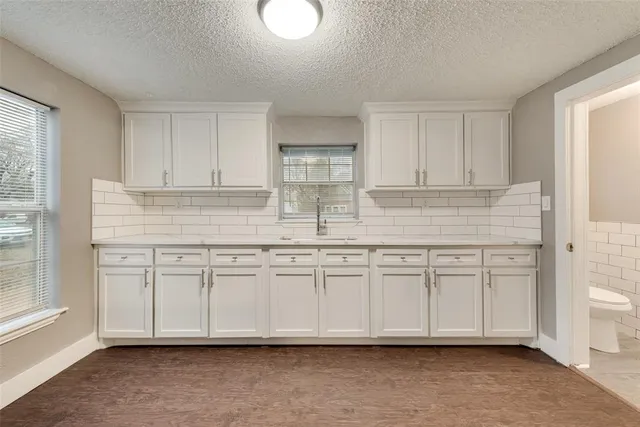 a kitchen with granite countertop white cabinets and a sink