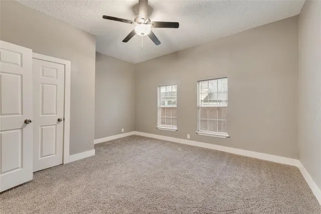 an empty room with windows and fan