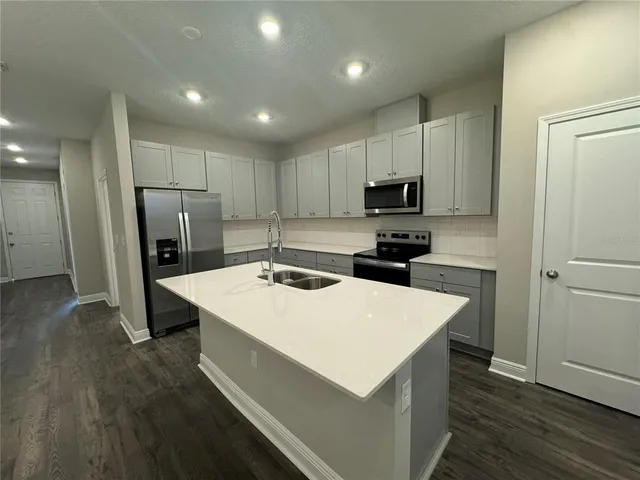 a kitchen with a refrigerator a stove top oven a refrigerator and white cabinets with wooden floor