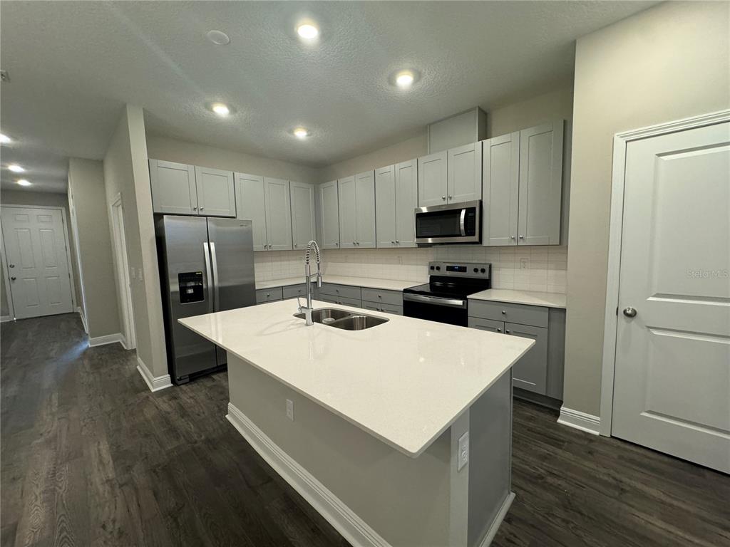 16333 Hamlin Hills Road Winter Garden, FL 34787 - Photo 13 of 35 a kitchen with a refrigerator a stove top oven a refrigerator and white cabinets with wooden floor