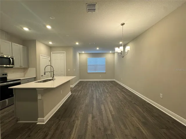 a view of a kitchen with kitchen island a sink wooden floor and a refrigerator