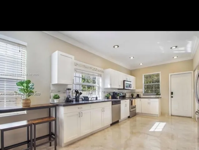 a kitchen with white cabinets and window