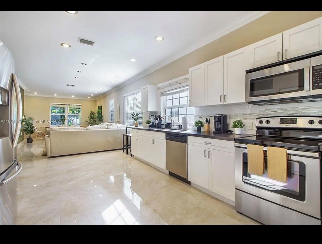 149 Northwest 48th Street Miami, FL 33127 - Photo 8 of 24 a kitchen with stainless steel appliances kitchen island granite countertop a stove sink and cabinets