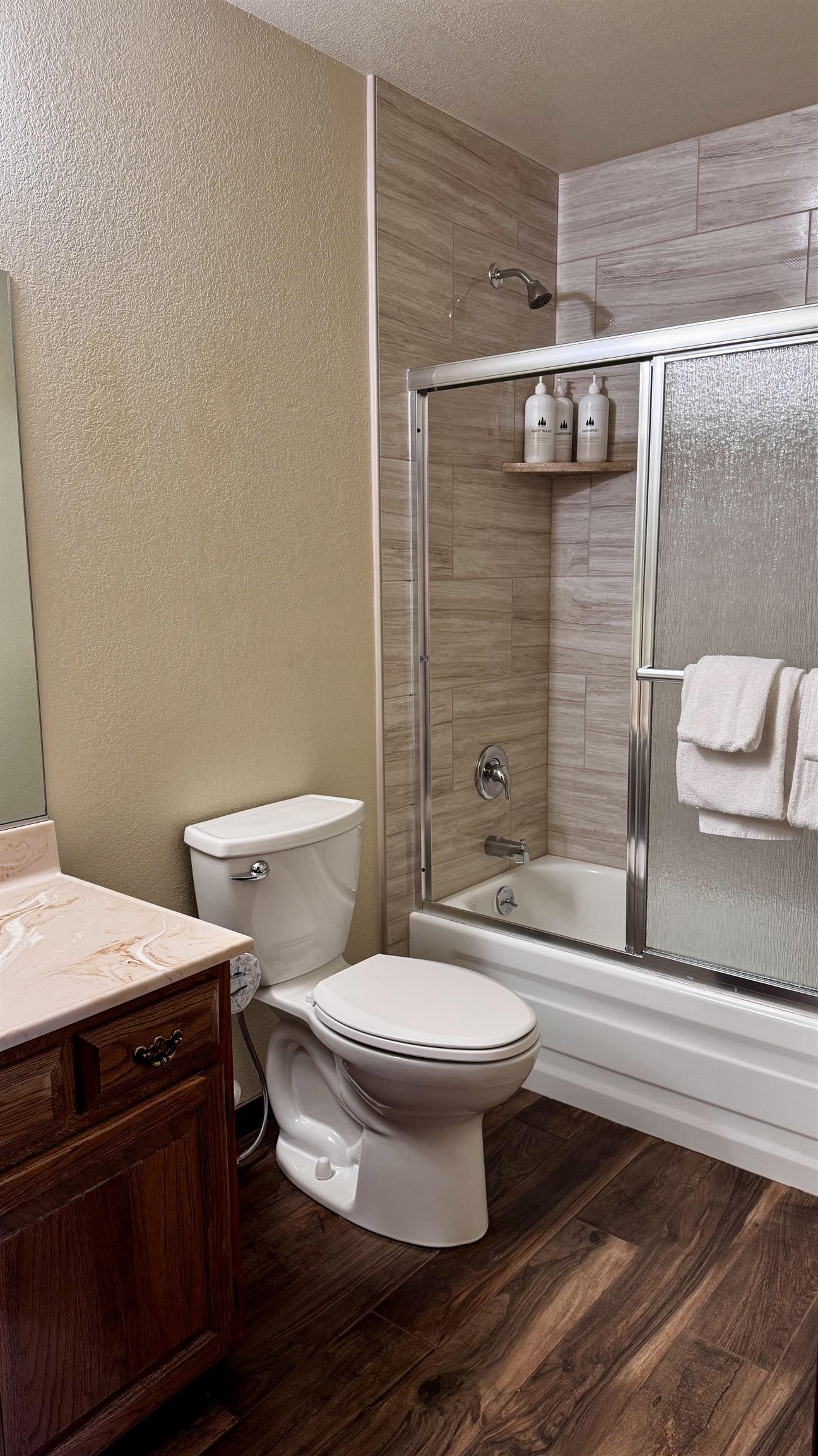4710 Minaret Road, Unit 87 Mammoth Lakes, CA 93546 - Photo 33 of 44 Bathroom featuring dark wood-style flooring, vanity, bath / shower combo with glass door, a textured wall, and a textured ceiling