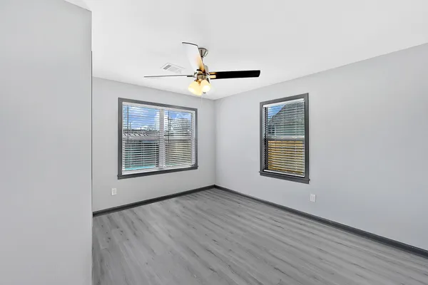 a view of an empty room with a window and a chandelier fan