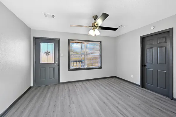 a view of an empty room with a window and wooden floor