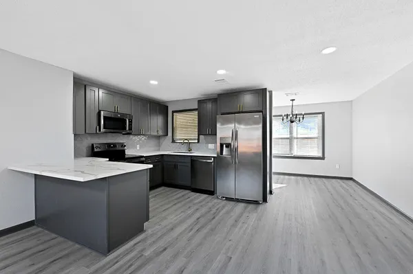 a kitchen with stainless steel appliances granite countertop a refrigerator a sink dishwasher a stove top oven a refrigerator with wooden floors and cabinets