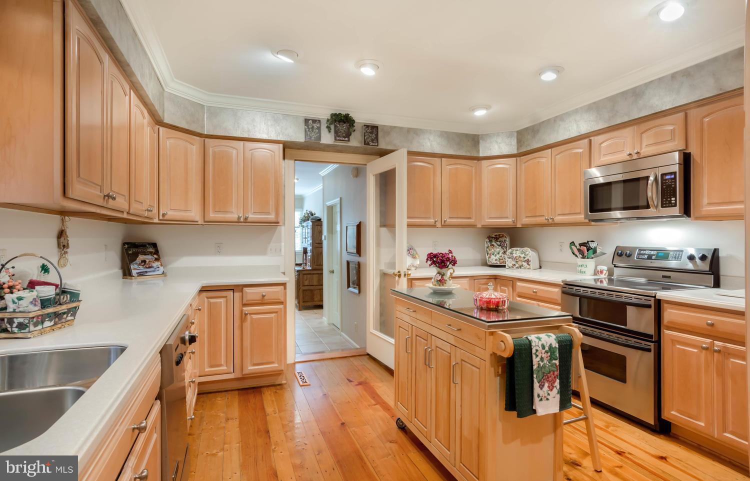 7301 Solitude Road St. Michaels, MD 21663 - Photo 21 of 30 a kitchen with stainless steel appliances granite countertop a stove top oven a sink a refrigerator and white cabinets with wooden floor