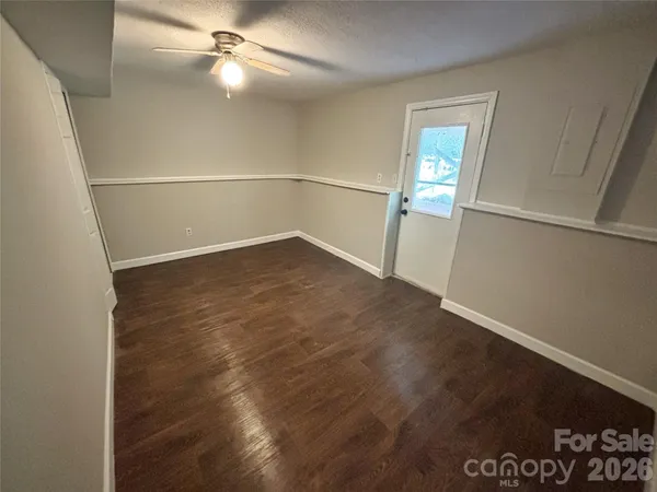 an empty room with wooden floor fan and windows