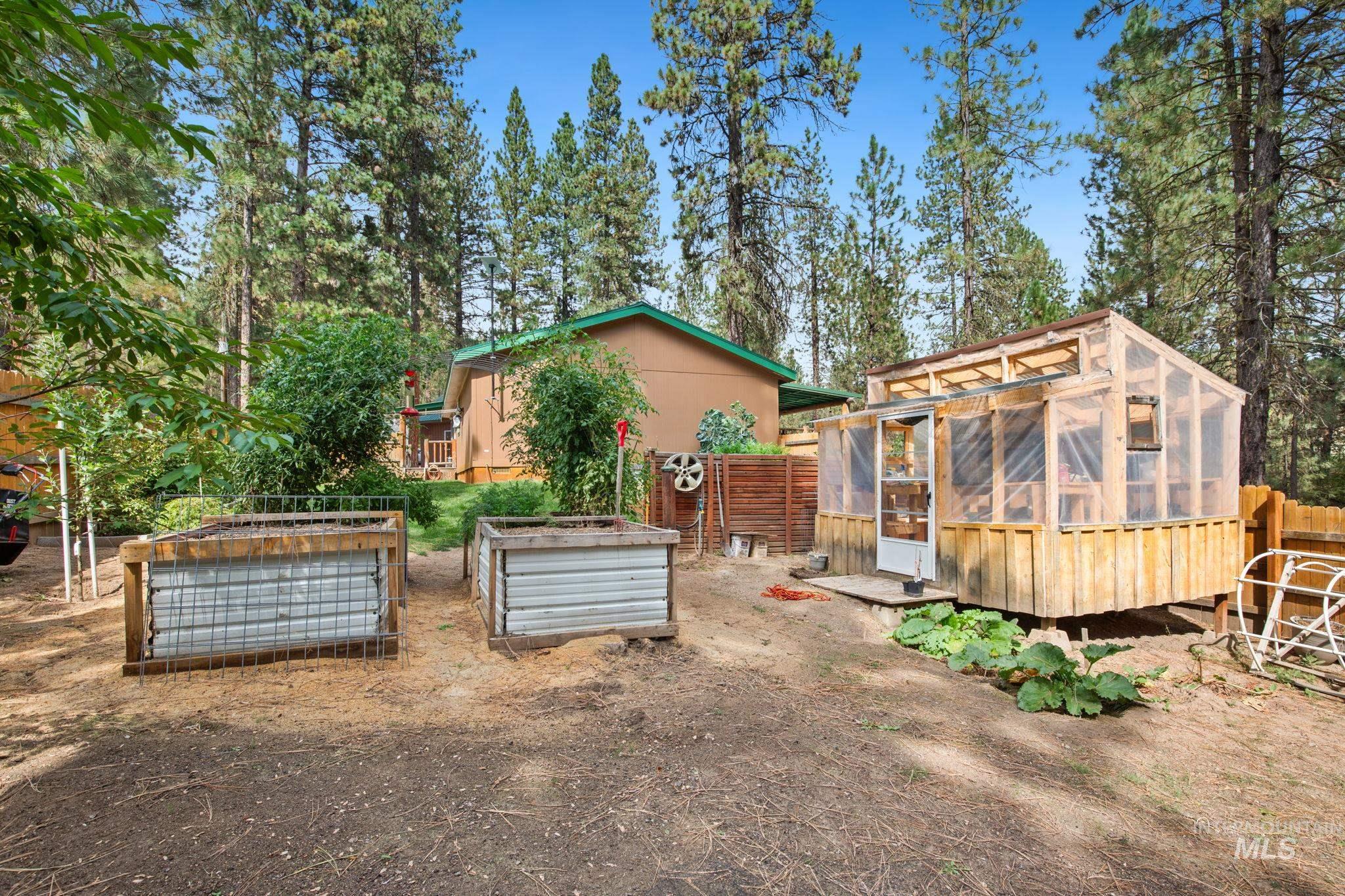 10 Cricket Road Garden Valley, ID 83622 - Photo 17 of 50 View of yard featuring a sunroom, an outdoor structure, an exterior structure, and a garden